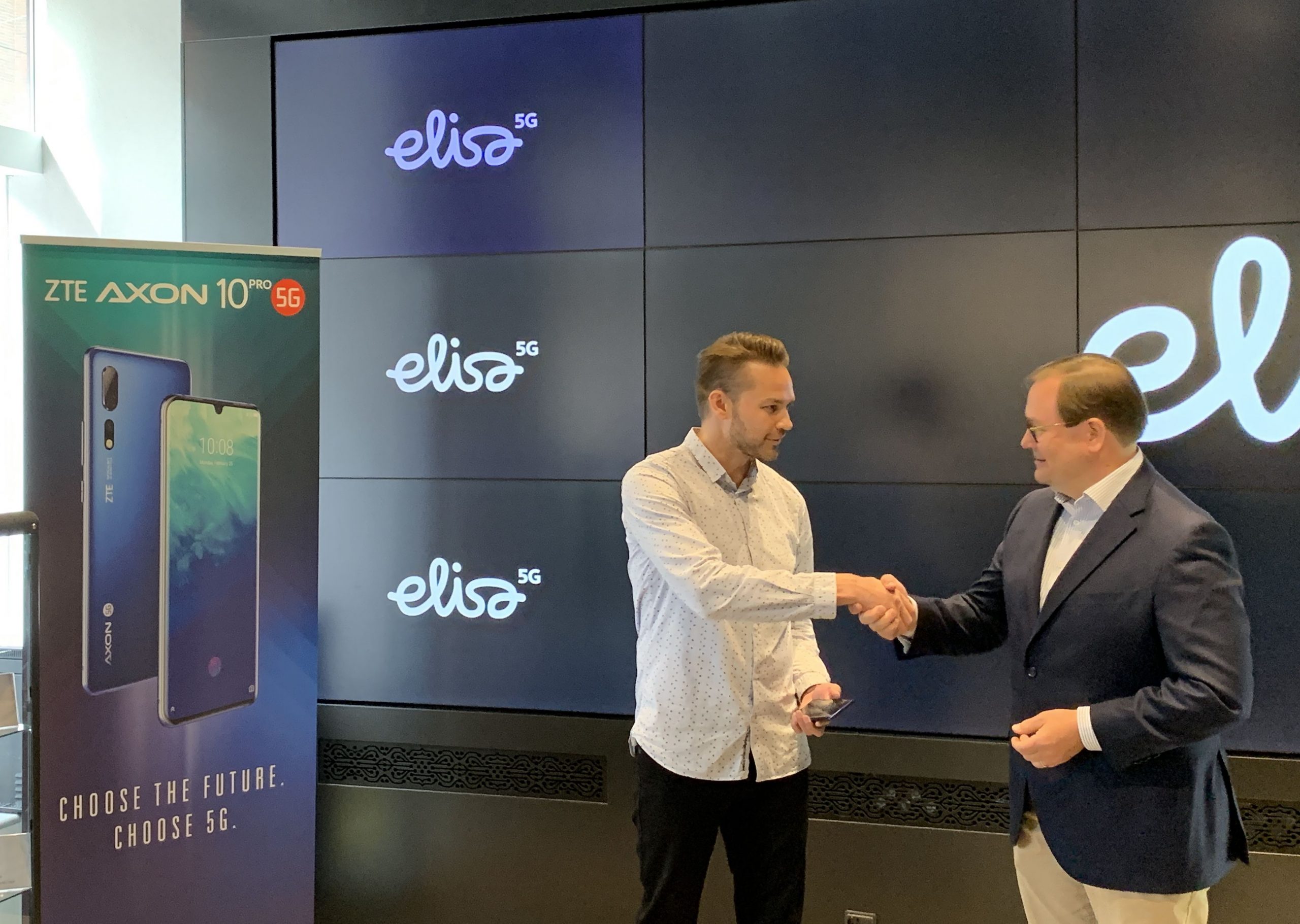 Elisan toimitusjohtaja Veli-Matti Mattila (oikealla) luovutti ensimmäisen 5G-älypuhelimen Suomessa asiakas Harri Hellströmille.